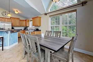 A kitchen with wooden cabinets, a central island, and a dining table with chairs. - Lake view 2BR with dock & deck, walk to the beach (Moultonborough)