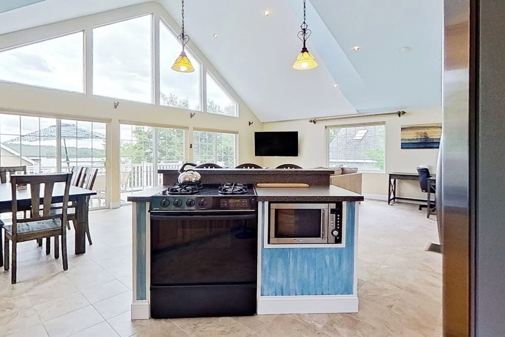 Una cocina moderna con horno empotrado, estufa a gas y microondas. Amplias ventanas que ofrecen luz natural y vistas al exterior.