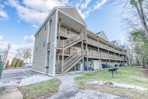 A multi-story building with a central staircase, balconies, and a covered outdoor area. - 1BR Lakeview 2nd-Floor - Balcony - Outdoor Pool (Gilford)