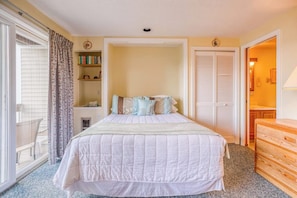A bedroom with a bed, a bookshelf, a wardrobe, and a sliding glass door. - 1BR Lakeview 2nd-Floor - Balcony - Outdoor Pool (Gilford)