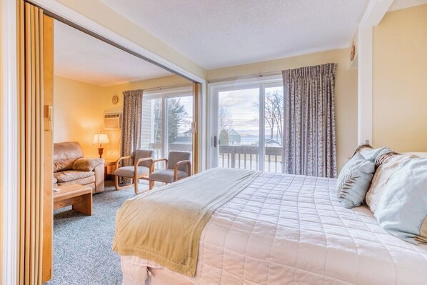 A hotel room with a bed, a sofa, a chair, and a view of the outdoors.