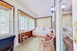 Ein Zimmer mit einem Bett, einem Sessel und einem Fenster mit Jalousien.
