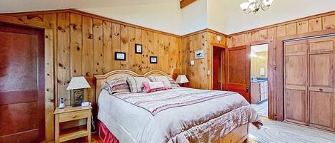 Ein Schlafzimmer mit einem hölzernen Kopfteil, einem Bett mit weißer und pinkfarbener Bettdecke, einem Nachttisch mit Lampe und einem Oberlicht über dem Bett.