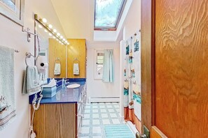 Casa de banho com lavatório, espelho e porta-toalhas.