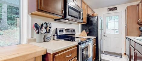 A kitchen with wooden cabinets, a microwave, stove, and a refrigerator.