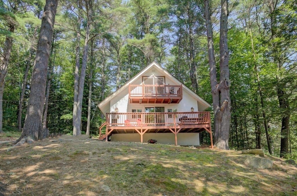 A cabin with a balcony, surrounded by trees.