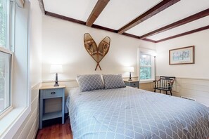 Ein Schlafzimmer mit einem Bett, Nachttischen, einem Sessel und einem Fenster.