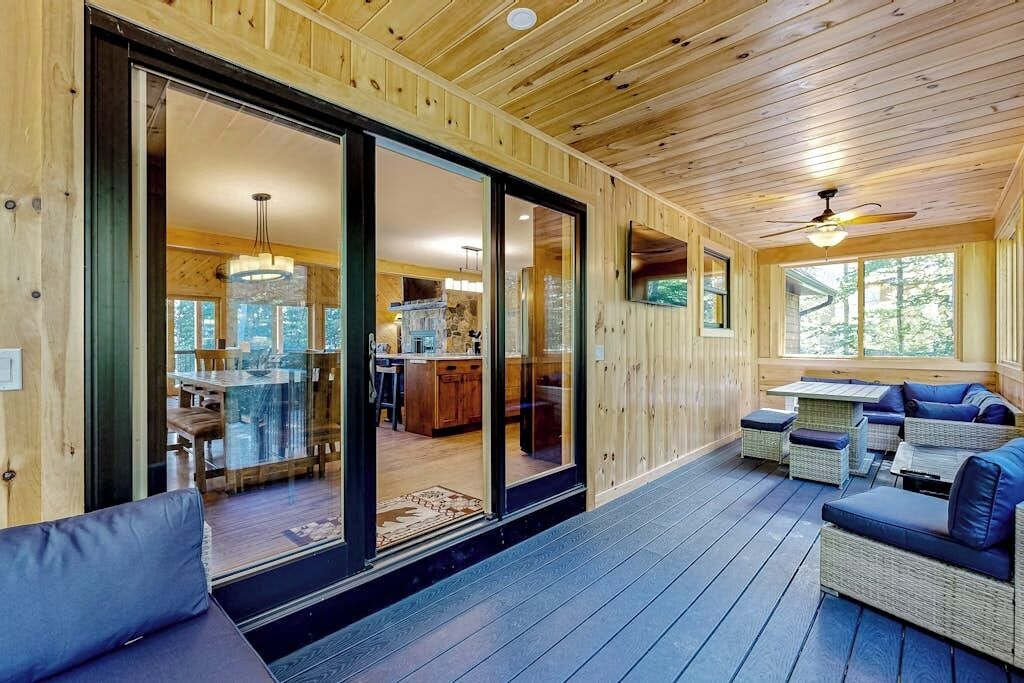Ein Holzhütten-Interieur mit Essbereich, Küche und einer Sitzecke mit Blick ins Freie.