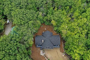 Una casa rodeada de un denso bosque, con un amplio camino de entrada y un garaje.