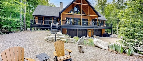 Un chalet doté d’une grande terrasse, de chaises en bois et d’une allée gravillonnée.