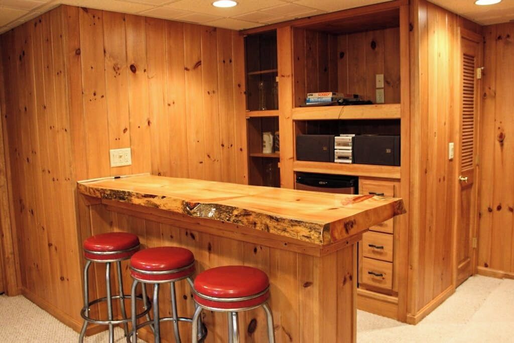 Uma área de bar com balcão de madeira, banquetes e estantes embutidas.