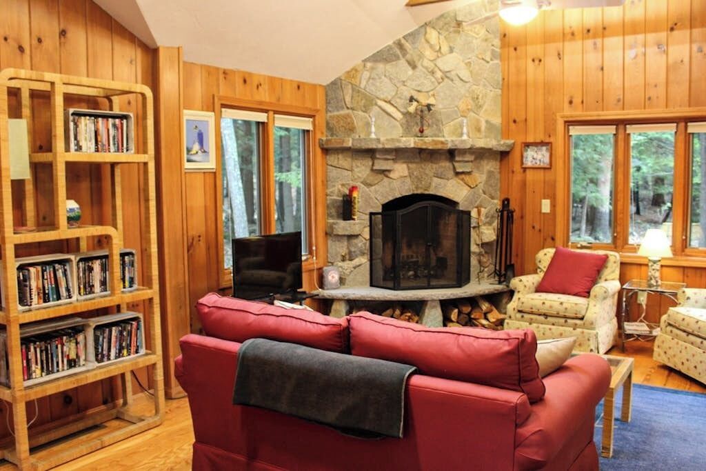 Un salon chaleureux avec une cheminée en pierre, des étagères en bois et des fauteuils confortables.
