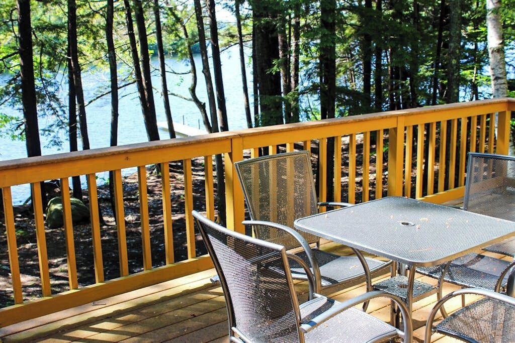 Une terrasse avec vue sur un lac, entourée d’arbres.