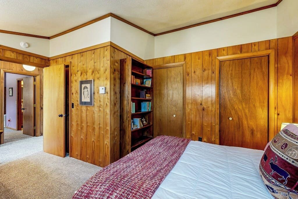 Ein Schlafzimmer mit einem großen Bett, einem Holzschrank und einem Bücherregal.