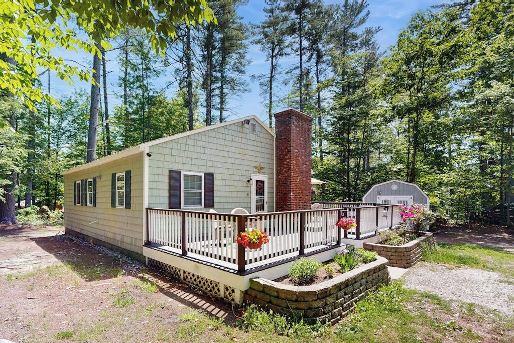 A single-story cabin with a fenced porch, a chimney, and a garage.