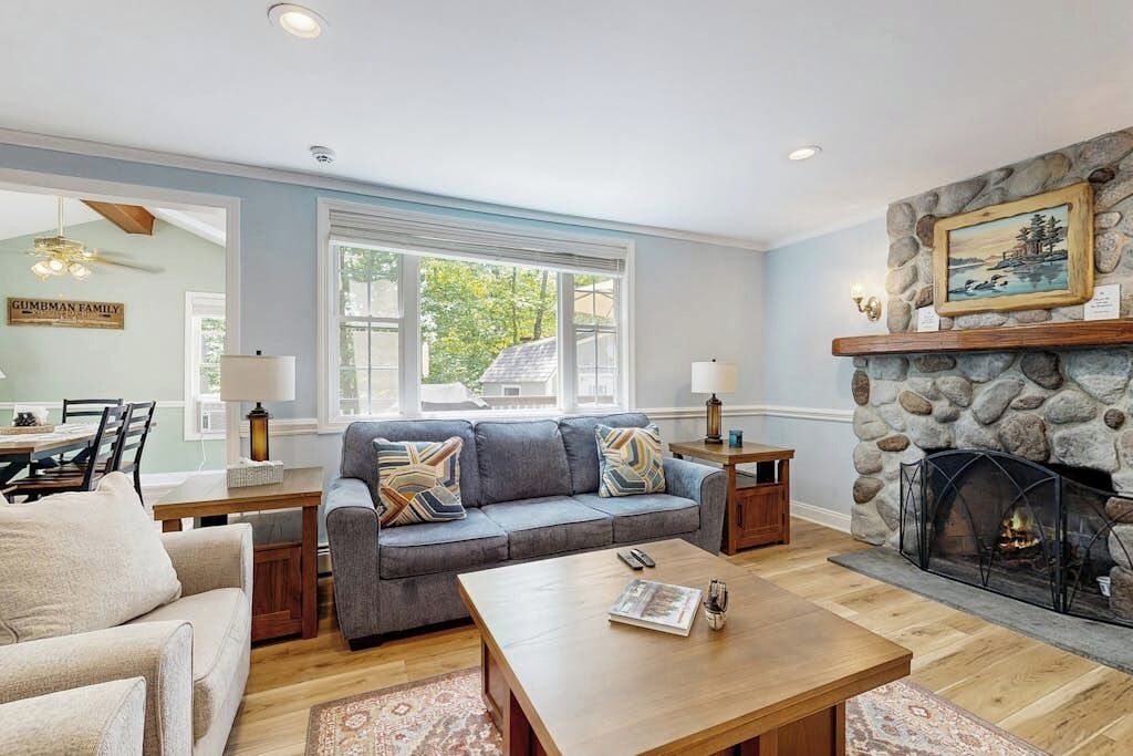 A living room with a sofa, coffee table, fireplace, and dining area.