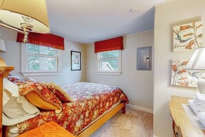 Een slaapkamer met een bed, een raam, een wandheater en een klein tafeltje met handdoeken.