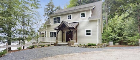 A two-story house with a front porch, a covered entryway, and a gravel driveway.