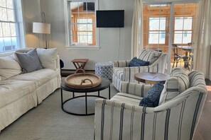 A cozy living room with a sofa, armchairs, a coffee table, and a TV mounted on the wall. - 3BR Fully renovated, dog friendly home (Meredith)