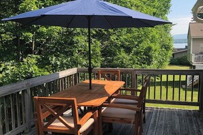 A wooden deck with a table and chairs under a blue umbrella. - 3BR Fully renovated, dog friendly home (Meredith)