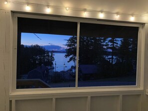 A window with a view of a body of water and trees at dusk. - 1BR cottage with beach access & dock (Alton)
