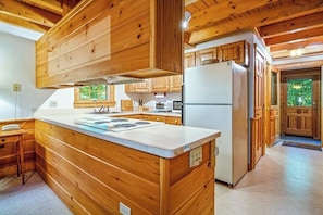 A kitchen with wooden cabinets, a white countertop, and a built-in refrigerator. - Charming 3BR Lakefront - Dock - Deck (Center Harbor)