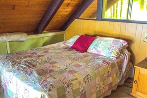 A single bed with a quilt in a room with wooden walls and a sloped ceiling. - Lakefront 1BR chalet with dock & amazing view (Meredith)