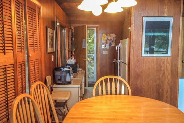 A wooden interior with a dining table and chairs, a kitchenette, and a window. - Lakefront 1BR chalet with dock & amazing view (Meredith)