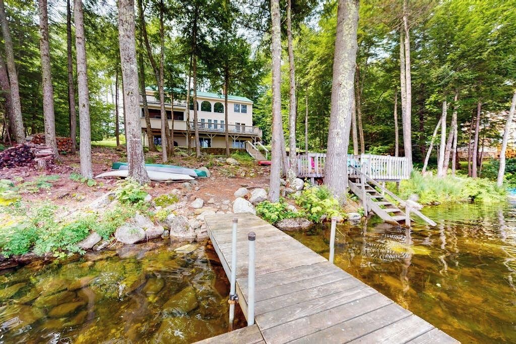 A wooden dock leading to a house surrounded by trees.