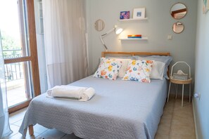 A neatly made bed with a white duvet and floral pillows, a bedside lamp, and a small bedside table with a tissue box. - Halkidiki Kassandra villa 3P Peace & Beautiful Sea (Agia Paraskevi)
