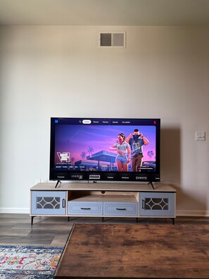 A television on a wooden stand with a wall-mounted vent above it. - The Nomad / Domain Rolex Building (Austin)