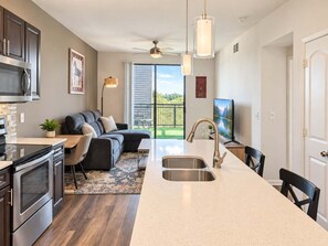 A modern kitchen with a central island, stainless steel appliances, and a dining area with a black chair.