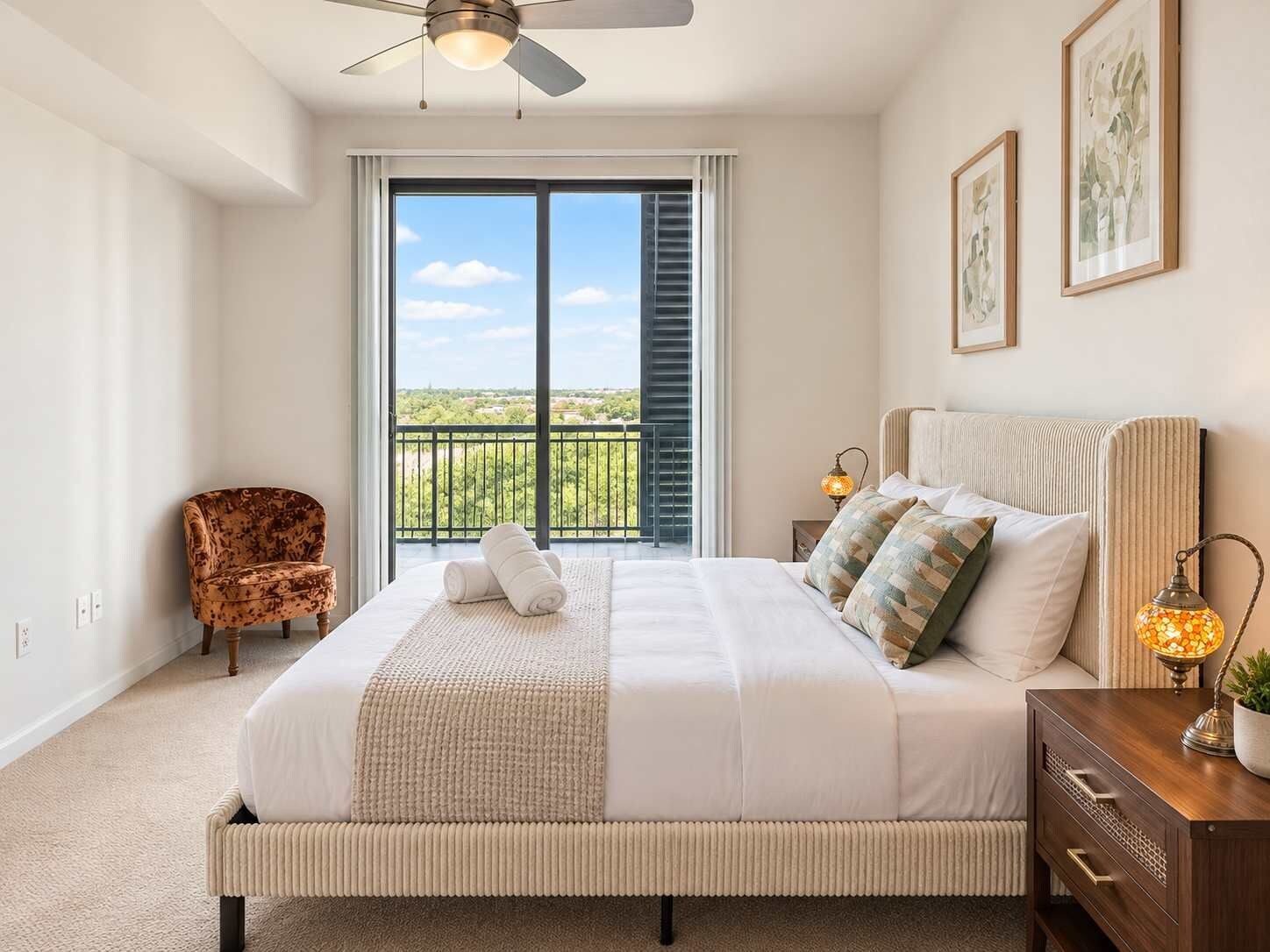 Une chambre avec un grand lit, une chaise, une table de chevet et une vue sur la verdure.