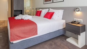 Une chambre d’hôtel moderne avec un grand lit, une table de chevet avec une lampe et des œuvres d’art accrochées au mur.