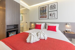A hotel room with a bed, a minibar, a shower area, and artwork on the wall. - Exclusive Luxury Beach Villa – Spacious & Private (Maputo)