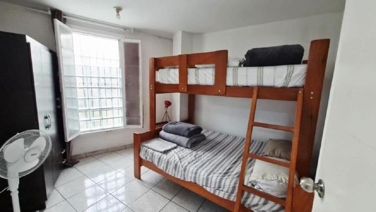 A bunk bed room with a fan, a window, and a door.