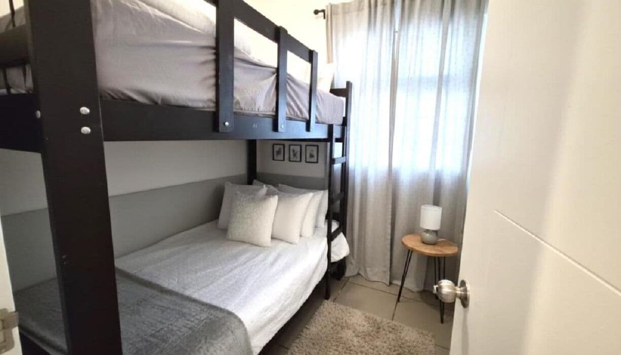 Habitación con literas, una mesita de noche pequeña y una lámpara.