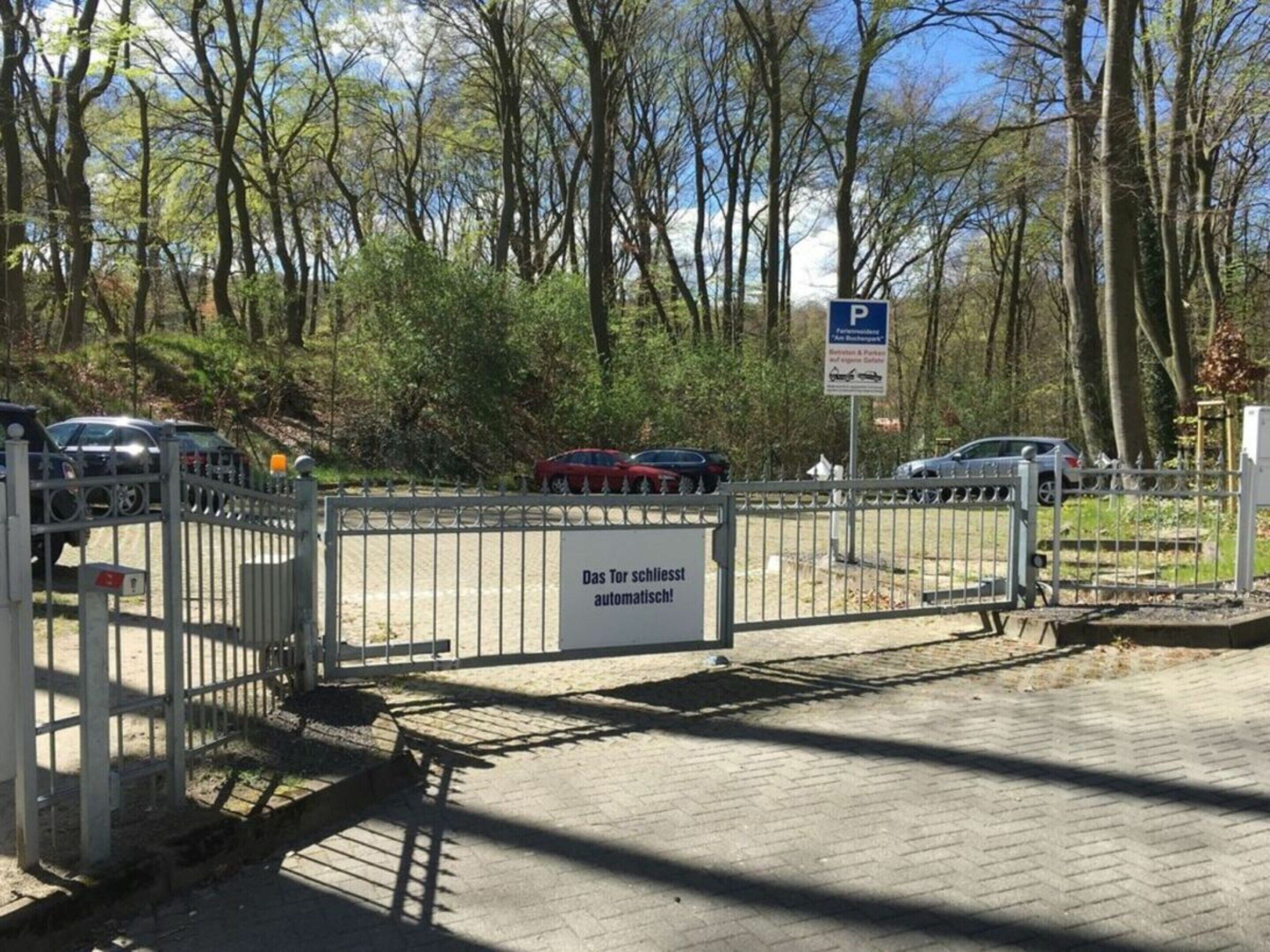 Un parking fermé par une barrière, avec un panneau indiquant qu’il est possible d’y payer automatiquement.