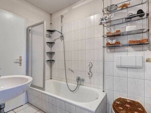 Ein Badezimmer mit einer Badewanne, einer Dusche, einem Waschbecken und einem Handtuchhalter mit verschiedenen Gegenständen.