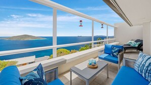 Un balcone con vista sul mare, ringhiere bianche e cuscini azzurri.