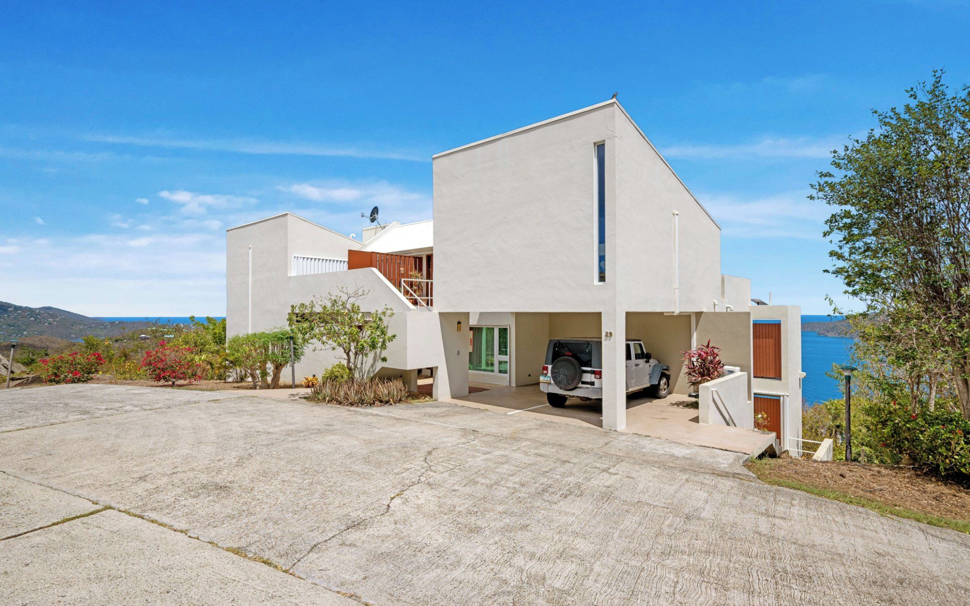 Une maison moderne à deux étages, dotée d’un garage, d’une allée et offrant une vue sur la mer.