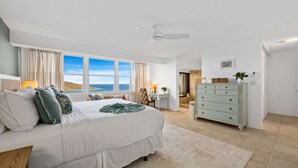 Una camera da letto con un letto, una cassettiera, una scrivania e vista sul mare.