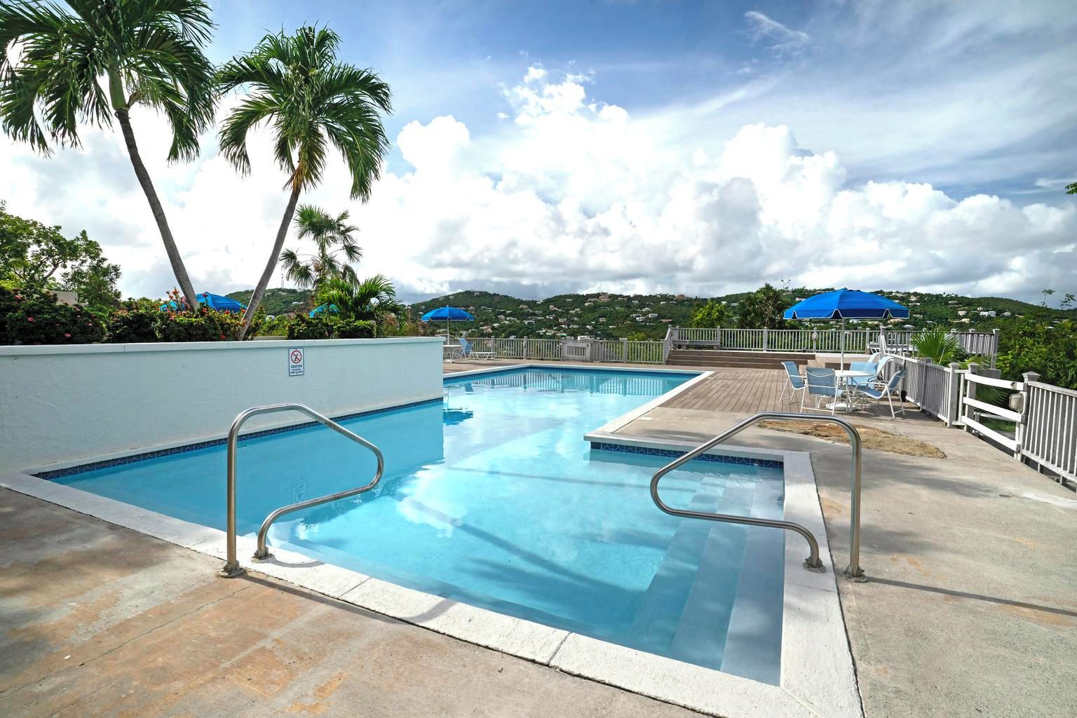 Ein Swimmingpool mit Sonnendeck, Liegestühlen und Sonnenschirmen.