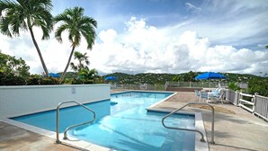 Una piscina con solarium, lettini e ombrelloni.
