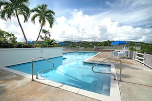 Une piscine dotée d’une terrasse, de chaises longues et de parasols.