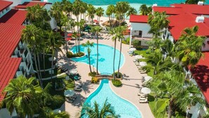 Un resort con piscina central, palmeras y vistas al océano.
