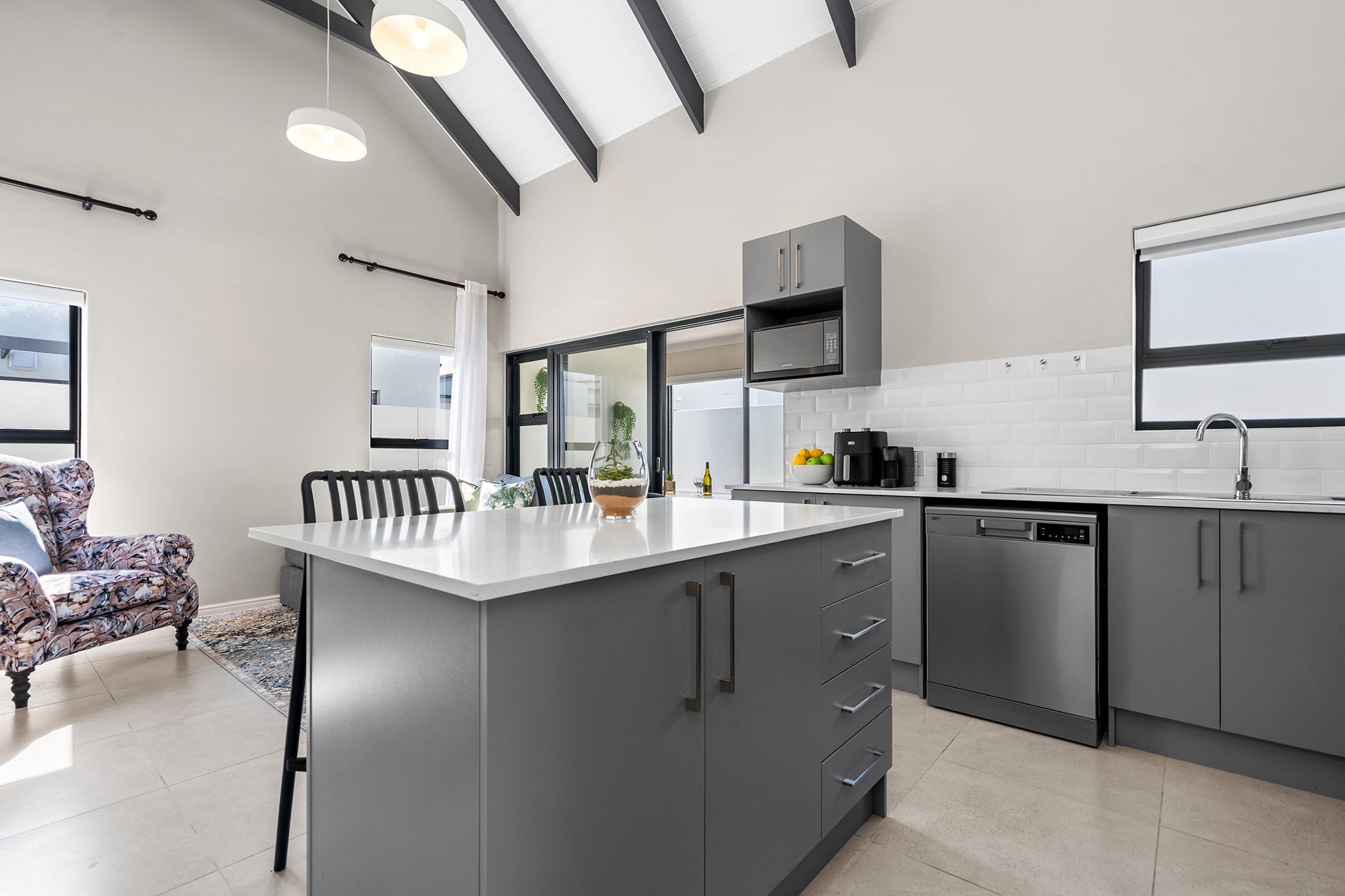 A modern kitchen with grey cabinetry, a white countertop, and a built-in oven.