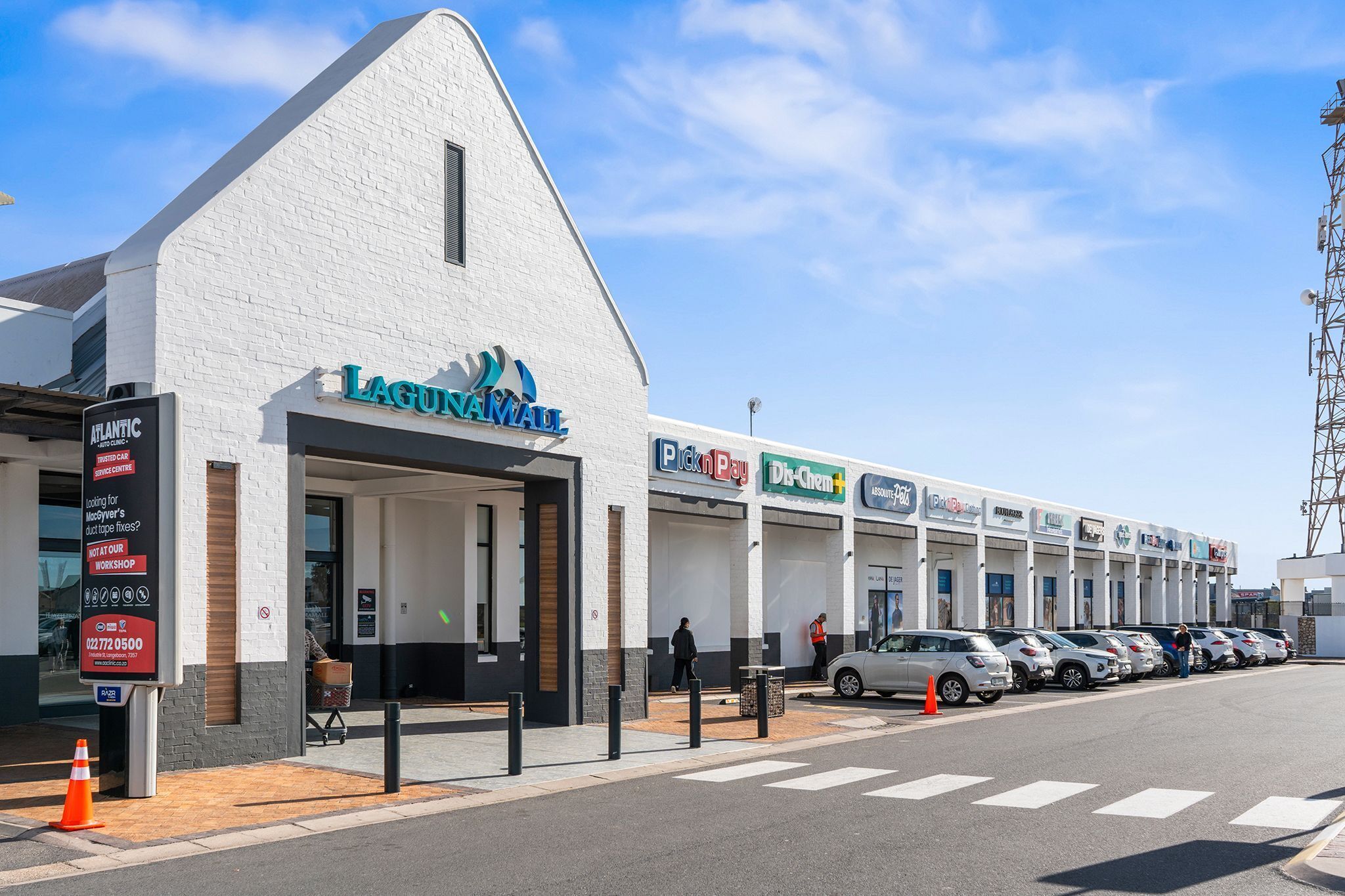 A building with a white facade, a sign for 'LAGUINAVAL,' and a row of parked cars.