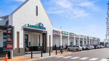 A building with a white facade, a sign for 'LAGUINAVAL,' and a row of parked cars.