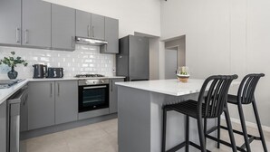Eine moderne Küche mit grauen Schränken, einem eingebauten Backofen, einer Kaffeemaschine und einem Kühlschrank.